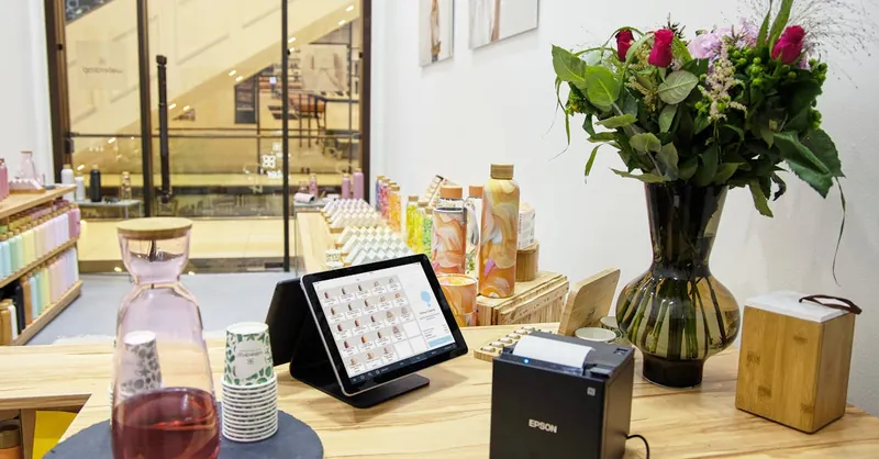 A stylish store checkout counter featuring a floral bouquet and digital payment system.