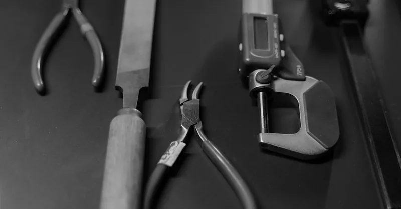 Monochrome image featuring various workshop tools arranged neatly on a surface.