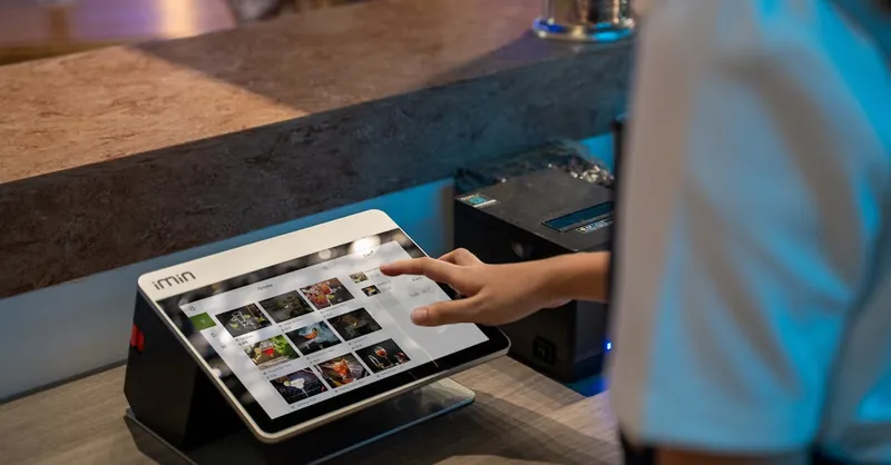 A close-up of a person interacting with a touchscreen in a restaurant setting, showcasing modern technology.