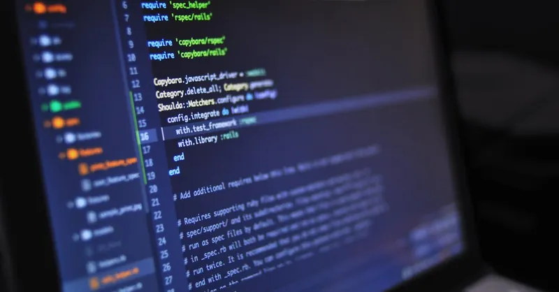 Close-up of a computer screen displaying programming code in a dark environment.