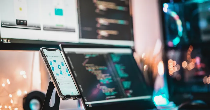 A close-up view of a tech setup with gadgets, coding screen, and smartphone, perfect for tech themes.