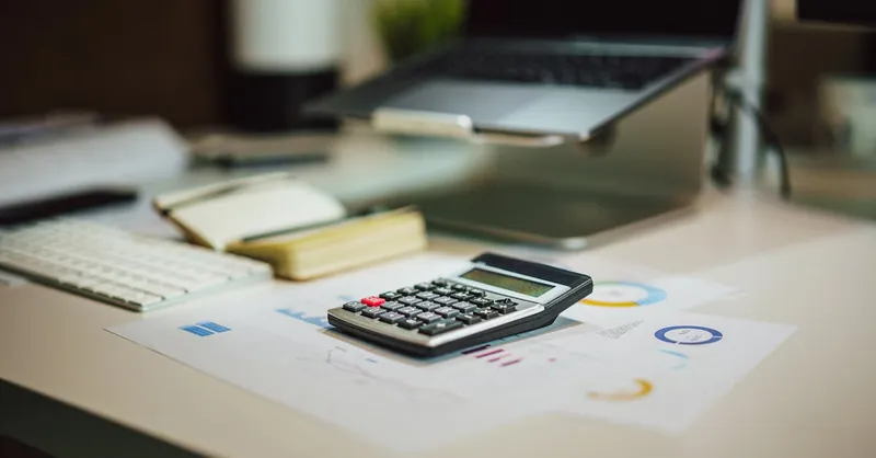 A modern workspace with a laptop, calculator, and documents on a desk, perfect for finance tasks.