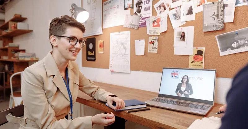 A woman engaged in an online English course session in a modern educational setting.