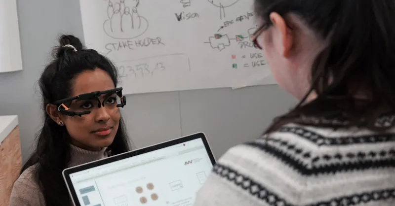 Two women conducting user testing with eye-tracking technology in an office setting.