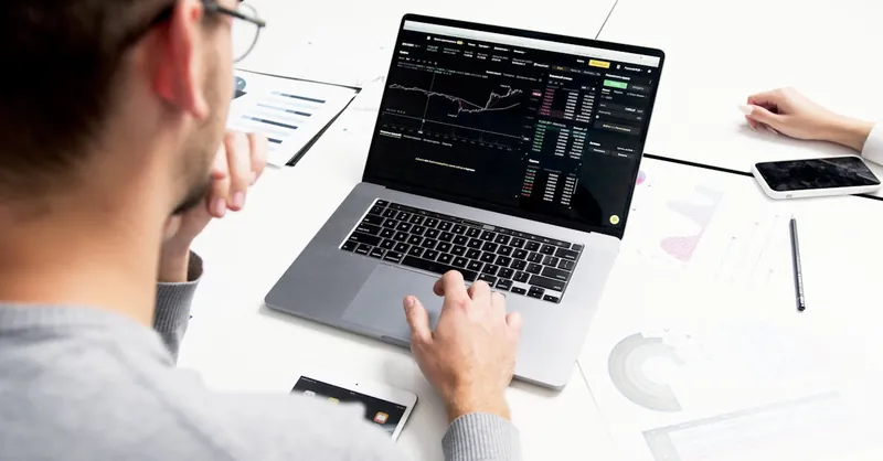 Business professional analyzing stock market data on a laptop for investment insights.