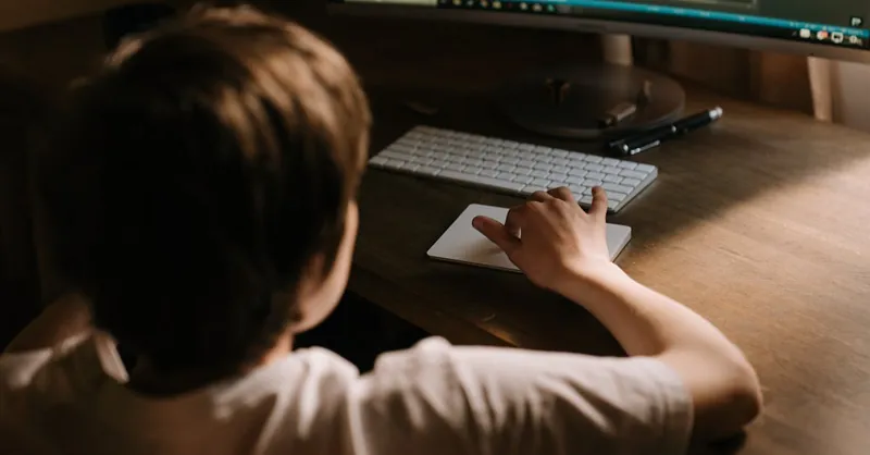 Teenager coding on a computer from a warm and cozy indoor setting, focused on software development.