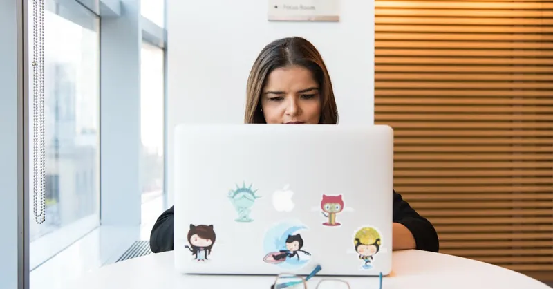 Woman in focus working on software development remotely on laptop indoors.